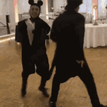 a man in a mickey mouse costume is dancing with another man in a cat costume