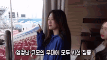 a woman in a blue hoodie is looking out a window