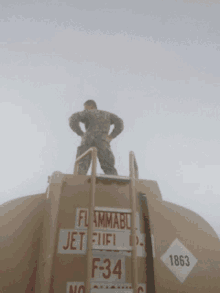 a man is standing on top of a jet fuel tank
