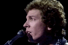 a man is singing into a microphone while playing a guitar .
