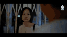 a woman in a white shirt is talking to a man in front of a fence with chinese writing on it ..