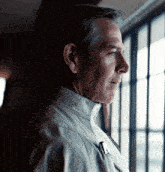a man is looking out a window and has a pen in his pocket