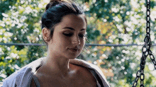 a woman is sitting on a swing with a towel on her shoulders .