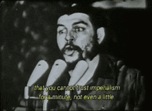 a man with a beard is speaking into a microphone and says that you cannot trust imperialism for a minute