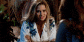 a woman in a white robe is sitting at a table with another woman .