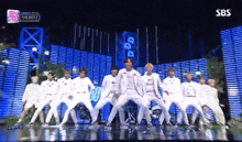 a group of men are dancing on a stage with a sign that says sbs on it