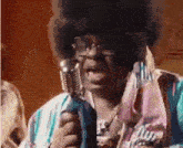 a man with an afro is singing into a microphone while wearing sunglasses .