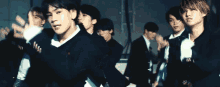a group of young men in suits and ties are dancing in a room .