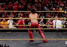 a wrestler in red pants is standing in a wrestling ring