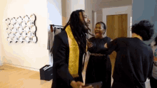 a group of people are standing in a room and one of them has a yellow sash around his neck