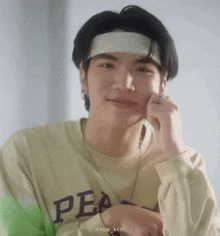 a close up of a young man wearing a headband and a necklace .