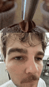a close up of a man 's face with chocolate frosting on his head