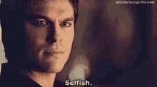 a close up of a man 's face with the words `` selfish '' written on his face .