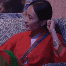 a woman in a red jacket is sitting on a couch with the words hum baaki cheez ke baare mein so