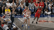 a female basketball player wearing a sun jersey dribbles the ball