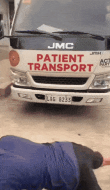 a white jmc patient transport truck is parked in front of a man