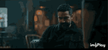 a man with a beard is holding a cup of coffee in his hand .