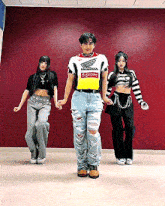 three people are dancing in front of a red wall and one of them is wearing a supreme shirt
