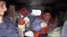 a group of people are sitting in a car and one of them is holding a bottle of water