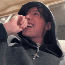 a man wearing a hoodie with a cross on it
