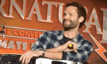 a man is sitting in front of a sign that says natural