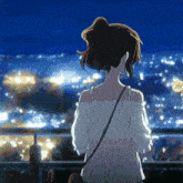 a girl is standing on a balcony looking out over a city at night .
