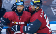 two hockey players are hugging and one has fortuna on his jersey