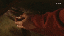a close up of a person 's hand with a max logo behind it
