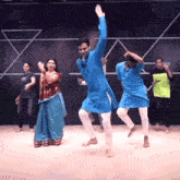 a man in a blue shirt is dancing with a woman in a red dress