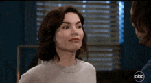 a woman in a white sweater is looking at a man .