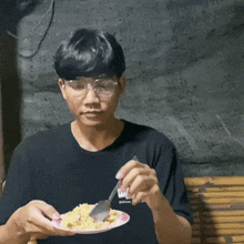 a man wearing glasses is eating a plate of food with a spoon