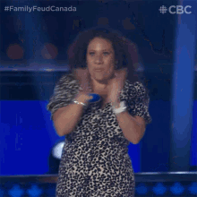 a woman in a leopard print dress is clapping her hands in front of a blue background .