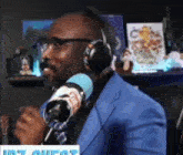 a man in a blue suit and headphones is talking into a radio microphone .