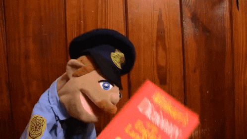 a puppet in a police uniform is holding a red book with the word dictionary on it