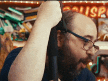 a man with a beard and glasses is standing in front of a sign that says ' sushi '