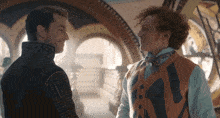 two men are standing next to each other and one of them has a vest that says ' e ' on it