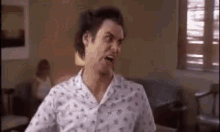 a man in a pajama shirt is making a funny face while standing in a living room .