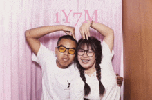 a man and a woman are posing for a picture with the word 1y7m behind them