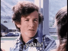 a man with curly hair is talking to a woman and says yeah !