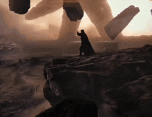 a painting of a man standing on top of a rocky hill with a giant in the background