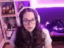 a young woman wearing headphones and glasses is sitting in front of a purple couch .
