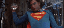 a man in a superman costume is standing in a room with a blue light behind him