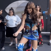 a woman in a blue skirt and cowboy boots is dancing in front of a group of women .