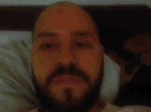 a man with a beard is laying in bed with his head on a pillow