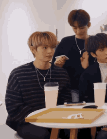 a group of young men are sitting around a table with cups and a tray on it