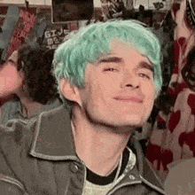 a man with green hair is smiling and making a face .