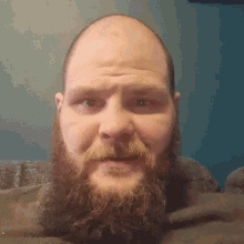 a man with a beard and a bald head looks down at the camera