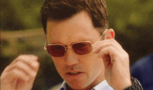 a man wearing a pair of sunglasses adjusts his glasses