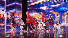 a group of people are dancing on a stage with a nbc logo in the corner .