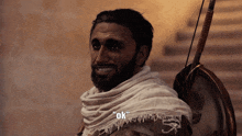 a man with a beard is holding a bow and shield and says ok